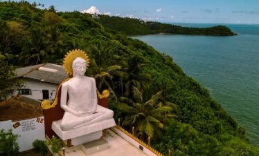 a statue of a person sitting on a bench by a body of water
