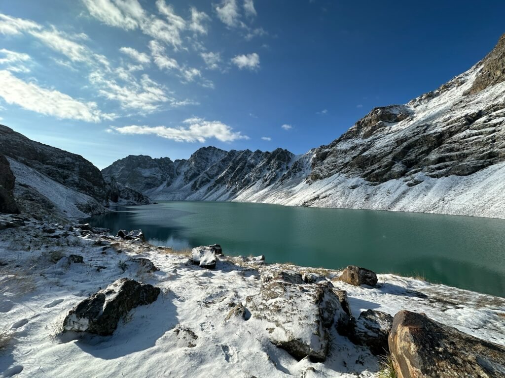 a lake surrounded by snow covered mountains under a blue sky