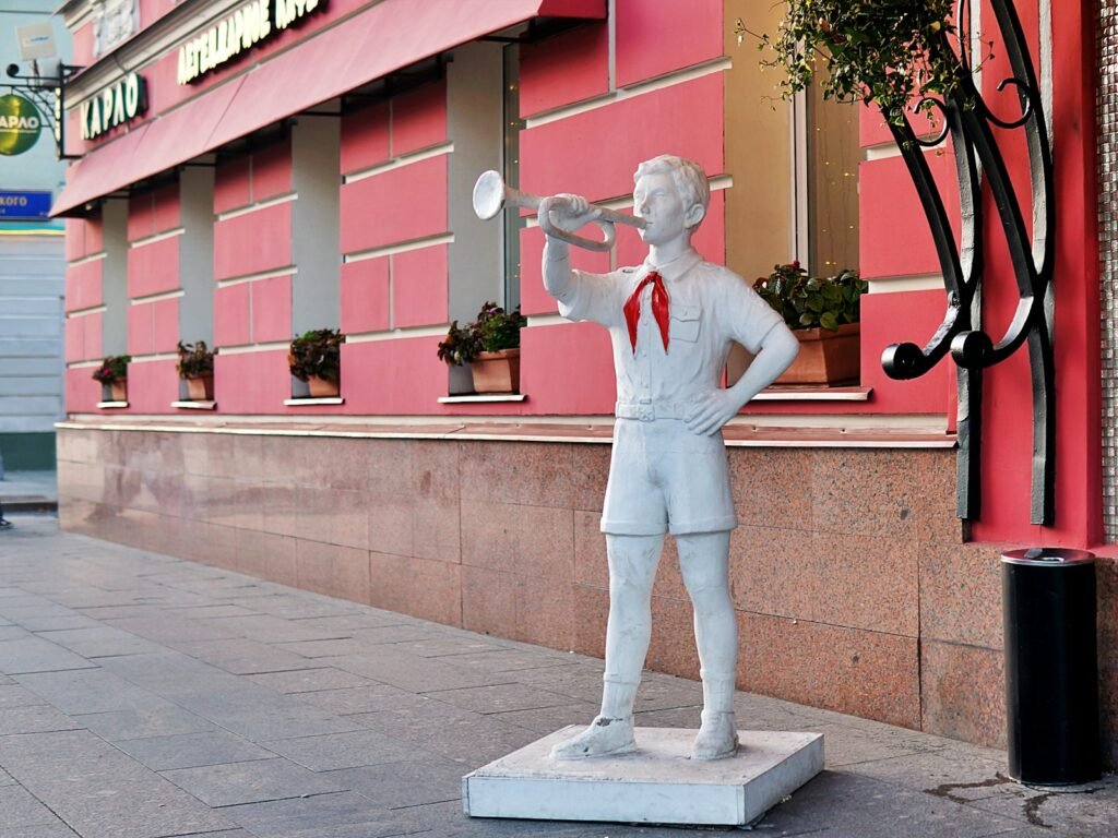 Statue of a boy playing a trumpet on a sidewalk.